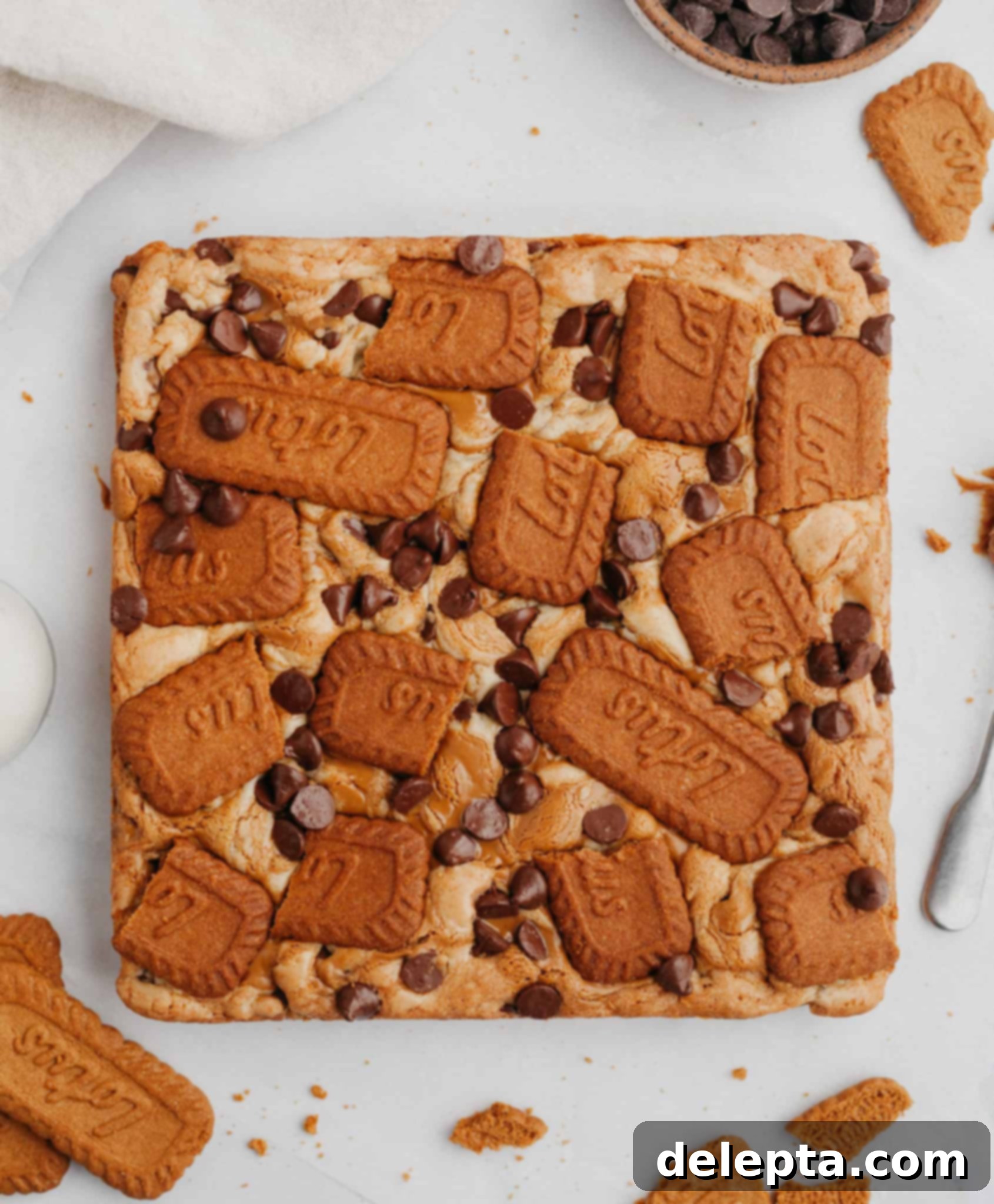 Easy One Bowl Brown Butter Biscoff Blondies 8 An overhead shot of freshly baked Biscoff blondies cooling on parchment paper, revealing their rich, swirled tops and chocolate chips.