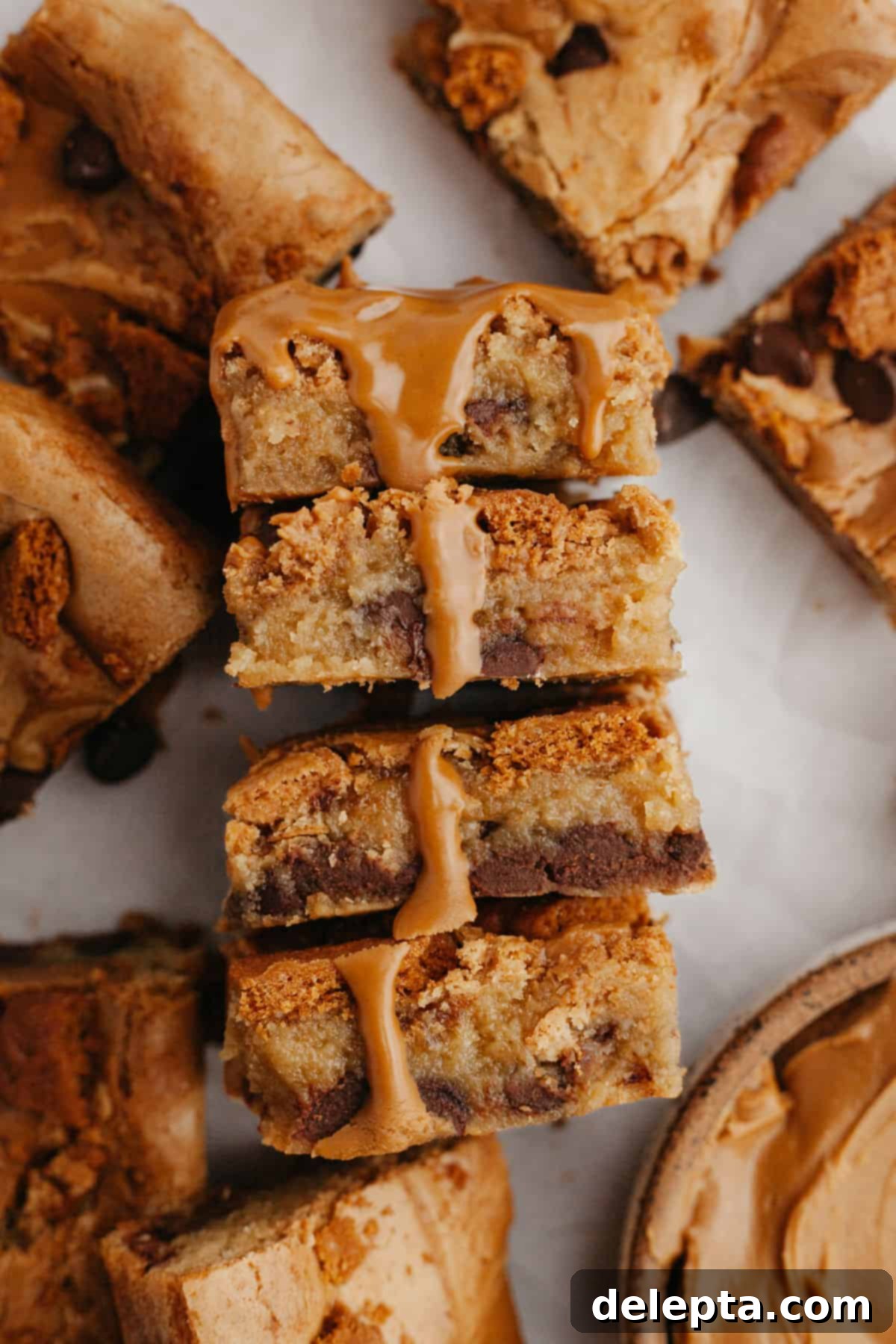 Easy One Bowl Brown Butter Biscoff Blondies 9 A stack of perfectly cut Biscoff blondies on parchment paper, showcasing their fudgy texture and cookie butter swirls.