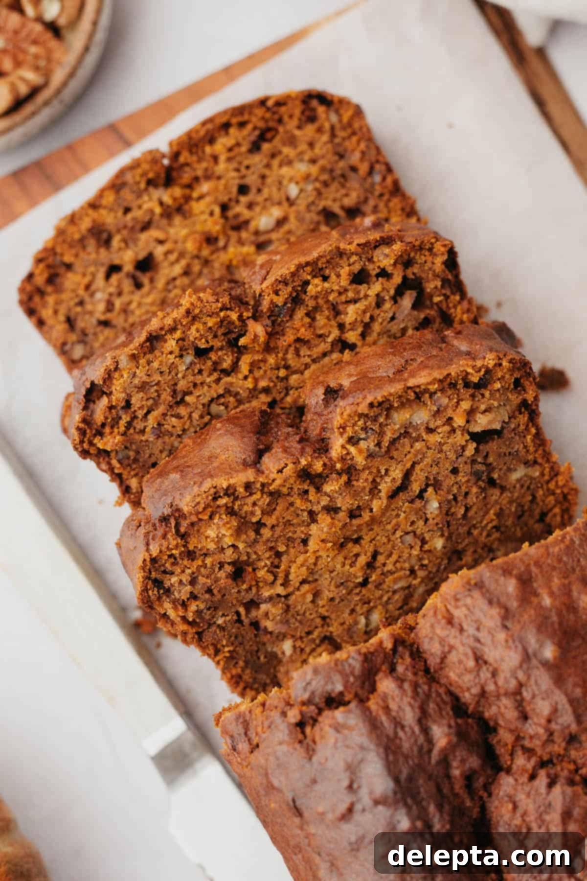 Effortless Pumpkin Carrot Banana Bread 6 An overhead shot of three slices of perfectly baked pumpkin banana bread on parchment paper.