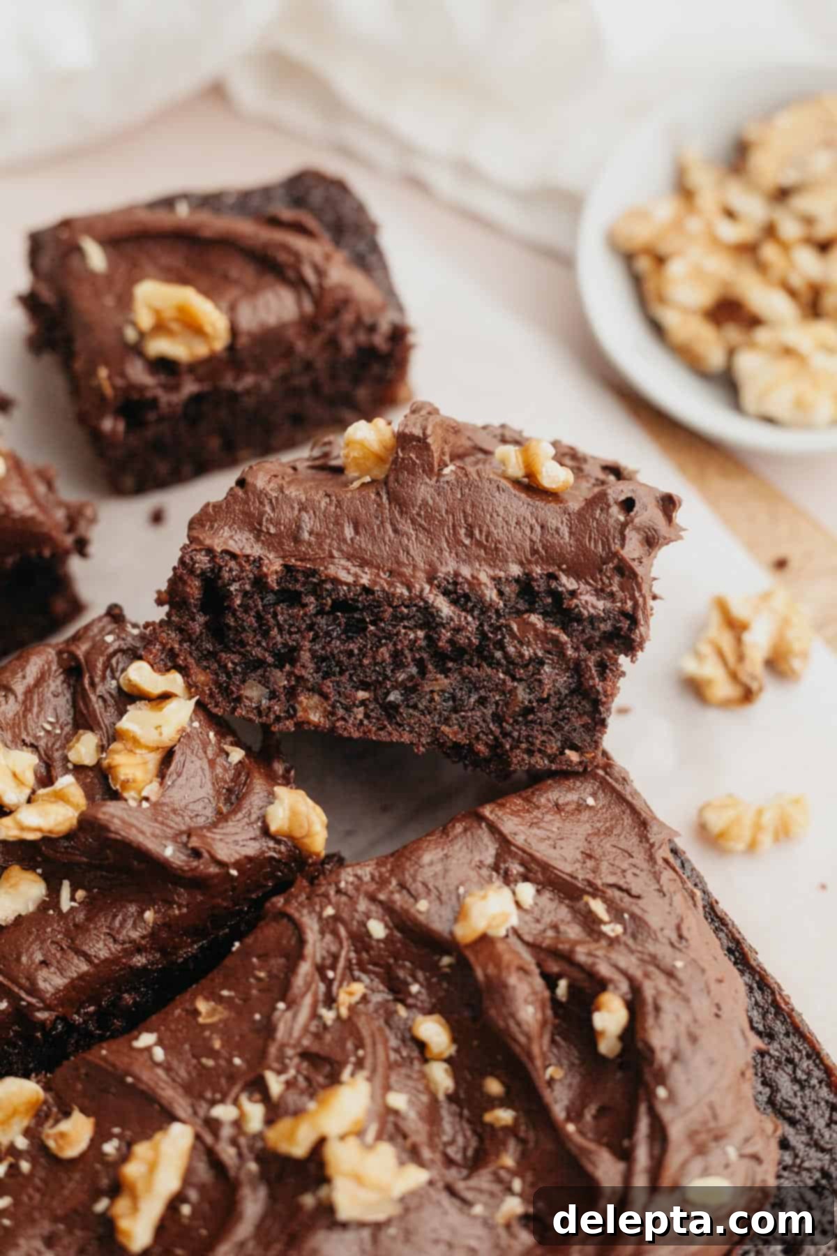 Simply Divine Moist Chocolate Walnut Cake 11 Multiple slices of chocolate cake with rich chocolate frosting and scattered crushed walnuts, ready to be served.