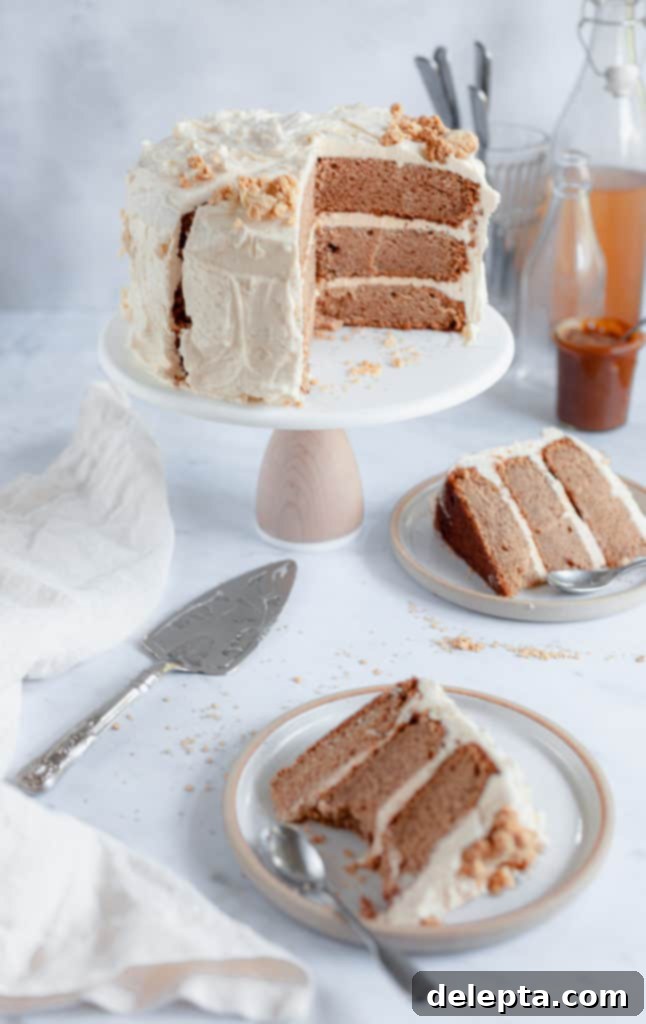 Salted Caramel Apple Cider Layer Cake with Pie Crumb Frosting 2 A stunning apple layer cake on a rustic stand, with two perfectly cut slices ready on plates, showcasing its rich layers and creamy frosting.