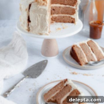 Salted Caramel Apple Cider Layer Cake with Pie Crumb Frosting 7 A stunning apple layer cake on a rustic stand, with two perfectly cut slices ready on plates, showcasing its rich layers and creamy frosting.