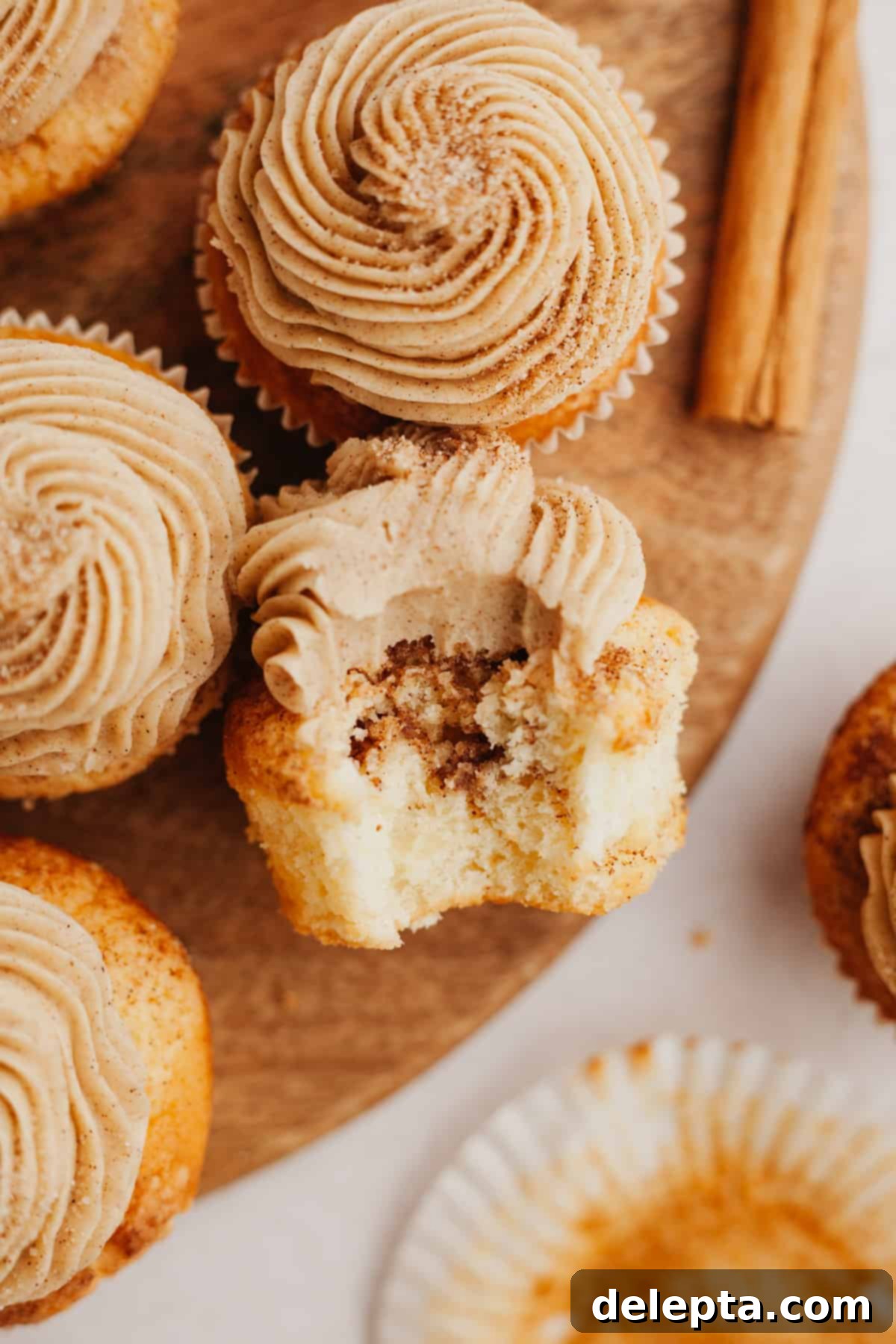 Spiced Cinnamon Cupcakes with Golden Brown Sugar Buttercream 2 A cinnamon swirl cupcake with a bite taken out of it, showing the delicious swirled interior and creamy frosting.
