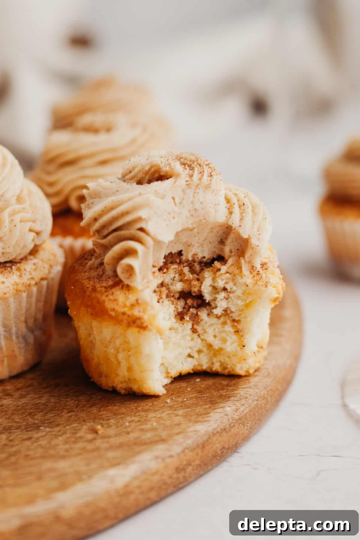 Spiced Cinnamon Cupcakes with Golden Brown Sugar Buttercream 10 A cinnamon swirl cupcake with a bite taken out of it, showcasing its delicious texture.