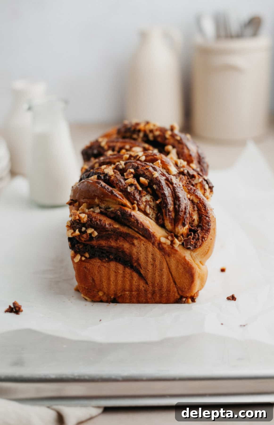 Decadent Nutella Babka 2 A perfectly baked Nutella babka on parchment paper, showcasing its beautiful swirls and golden crust.
