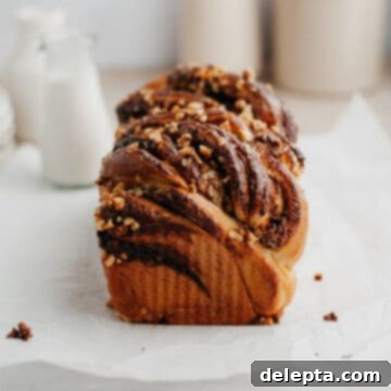 Decadent Nutella Babka 11 A beautifully baked Nutella babka, golden brown with visible swirls, resting on parchment paper.