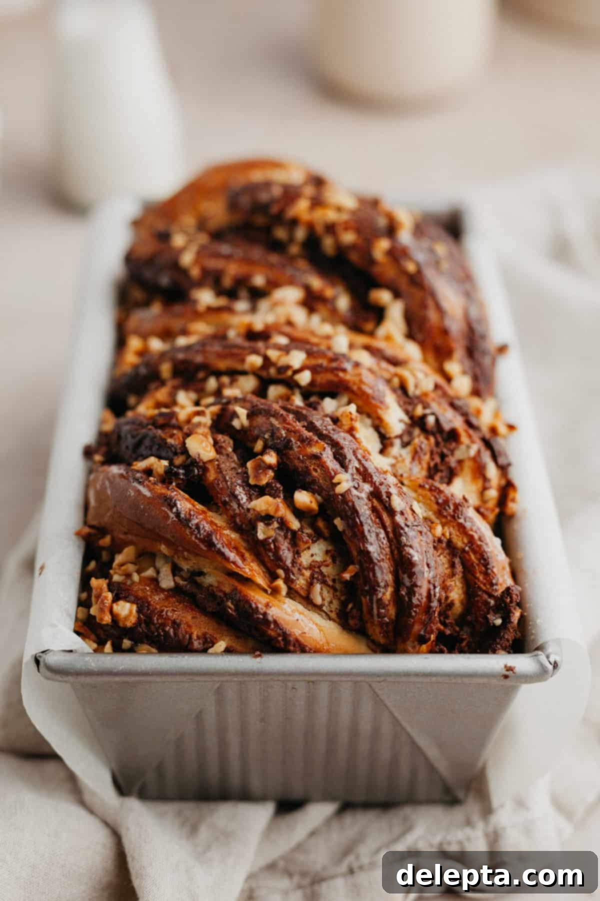 Decadent Nutella Babka 10 A close-up shot of a baked Nutella babka still in its loaf pan, showing the rich, swirled top.