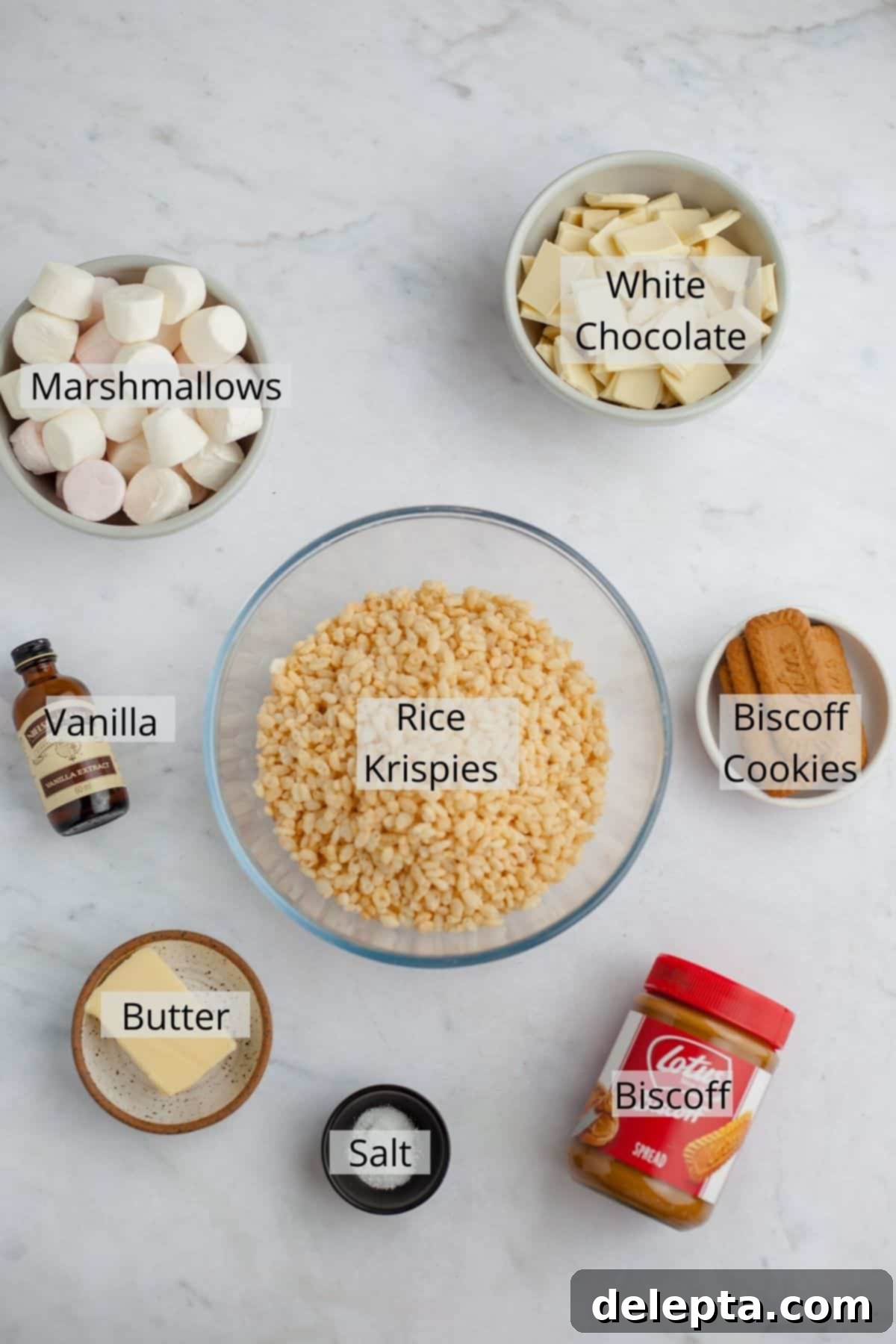 Ultimate Biscoff Krispie Bars 3 Ingredients for biscoff rice krispie treats laid out in bowls, including marshmallows, butter, biscoff spread, white chocolate, and rice krispies.