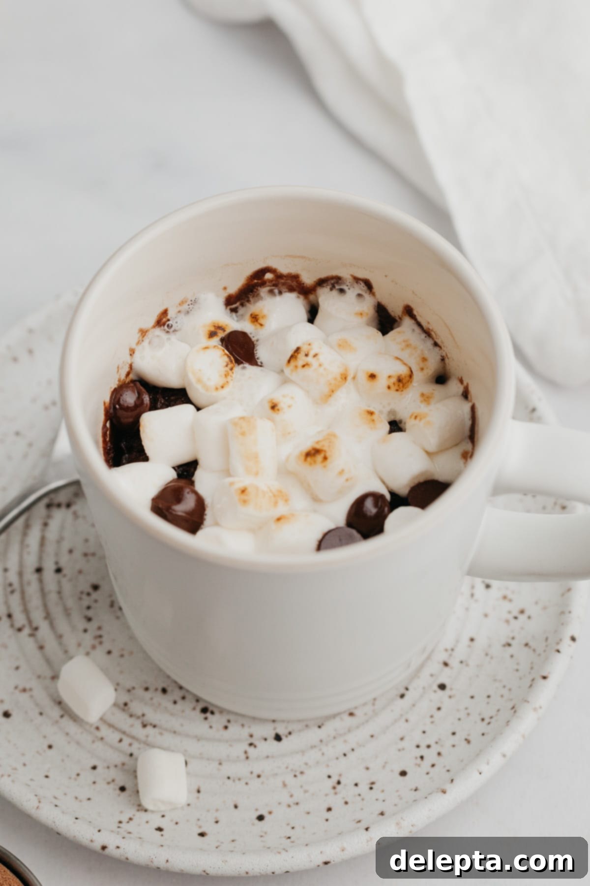 Mugful of Cocoa Bliss 2 A white mug with a chocolate mug cake generously topped with fluffy marshmallows.