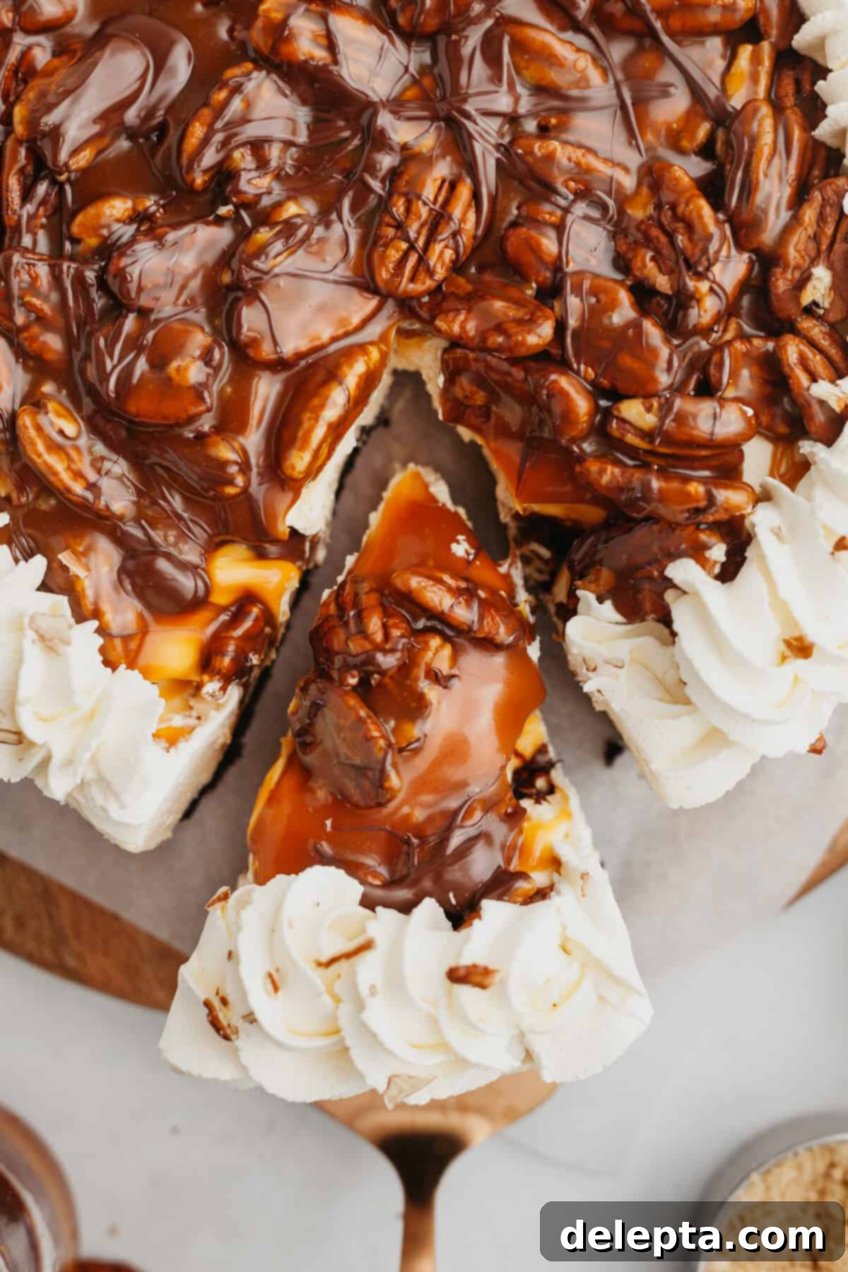 Irresistible No-Bake Turtle Dream 2 An overhead shot of a slice of turtle pie being lifted out, showcasing the rich layers of chocolate crust, creamy filling, caramel pecans, and whipped cream.