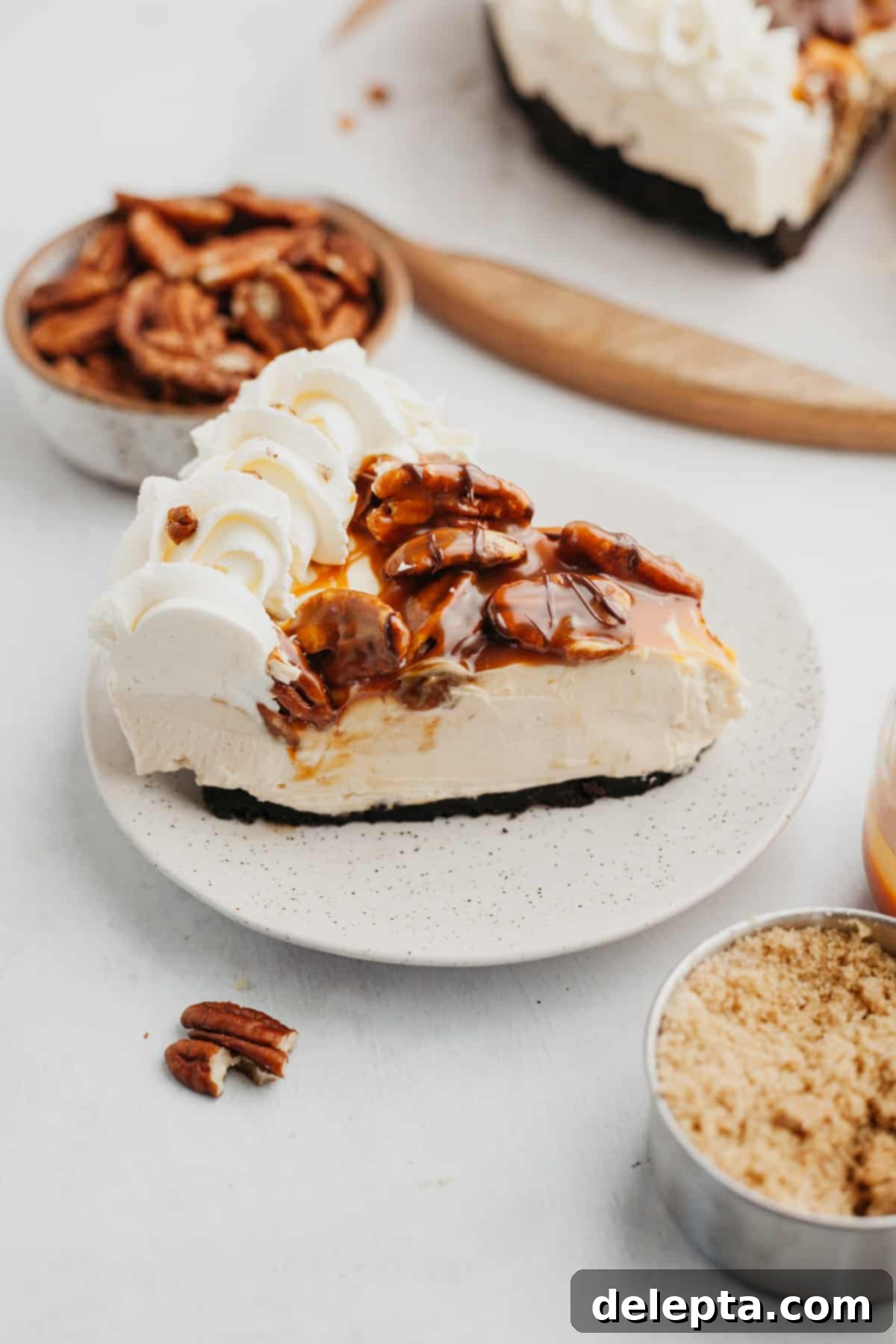 Irresistible No-Bake Turtle Dream 8 A perfectly sliced piece of cheesecake turtle pie, showing the layers of Oreo crust, creamy filling, and pecan topping, resting on a white plate.