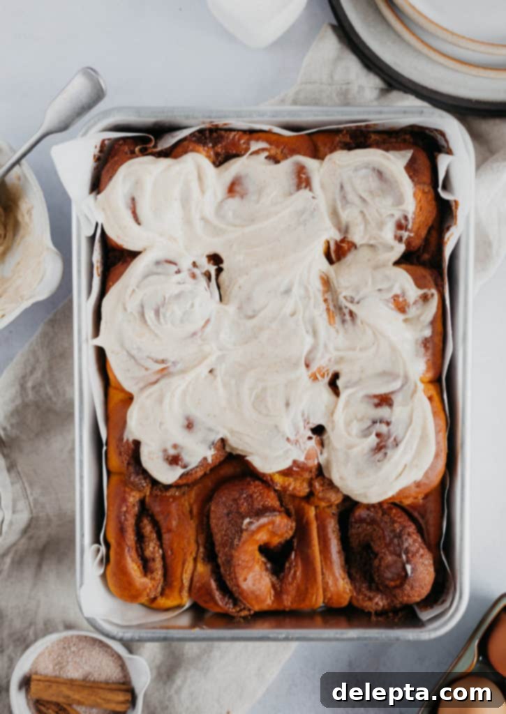 Warm Pumpkin Swirls with Brown Butter Glaze 3 overhead view of pumpkin cinnamon rolls, 9 of them frosted.