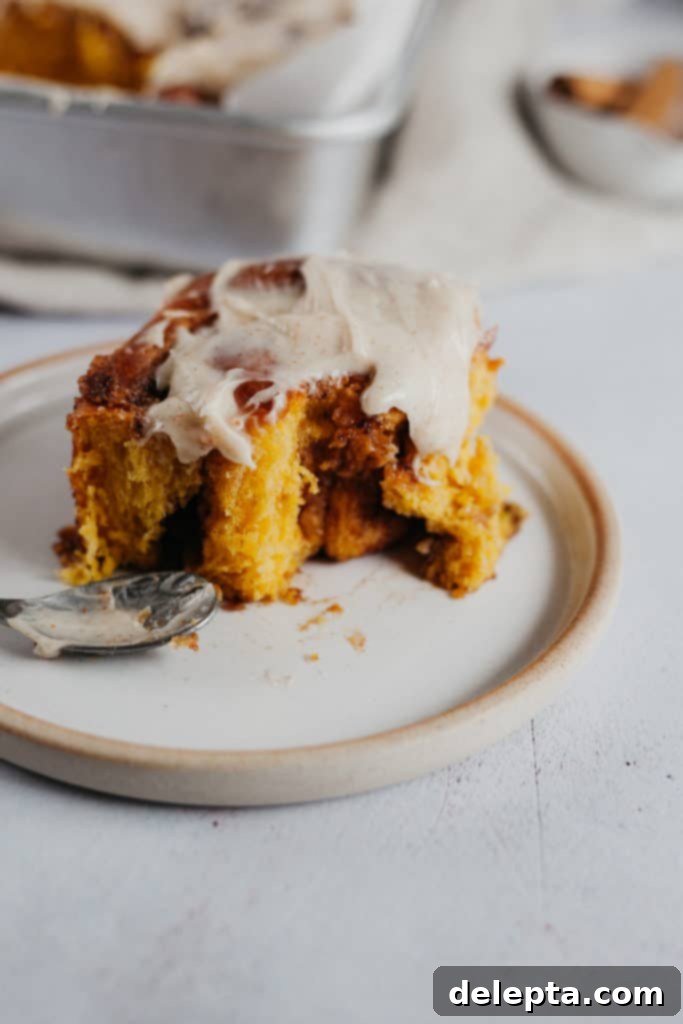 Warm Pumpkin Swirls with Brown Butter Glaze 5 one cinnamon bun on a plate with frosting