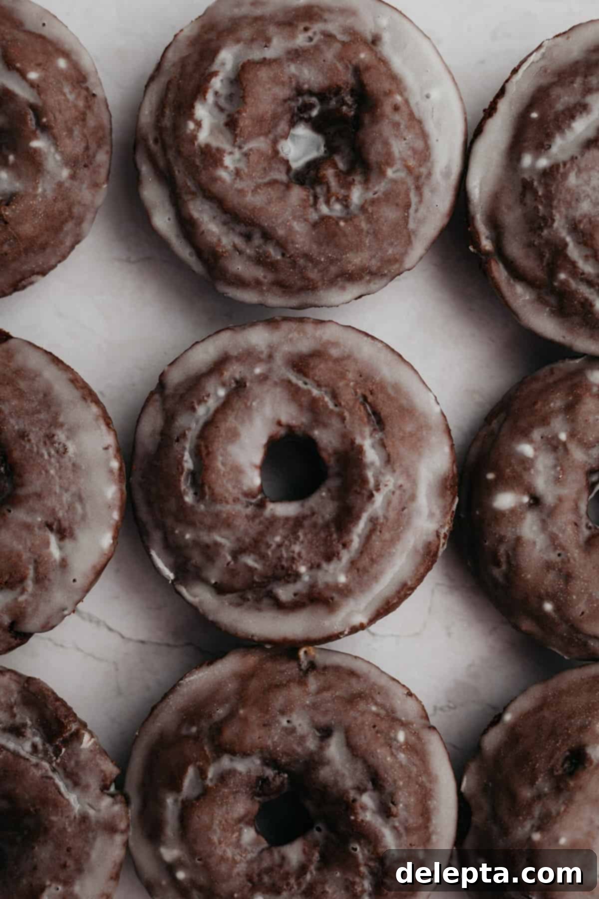 Decadent Glazed Chocolate Cake Doughnuts 8 Three perfectly arranged rows of chocolate doughnuts, each beautifully glazed, creating an appetizing display.