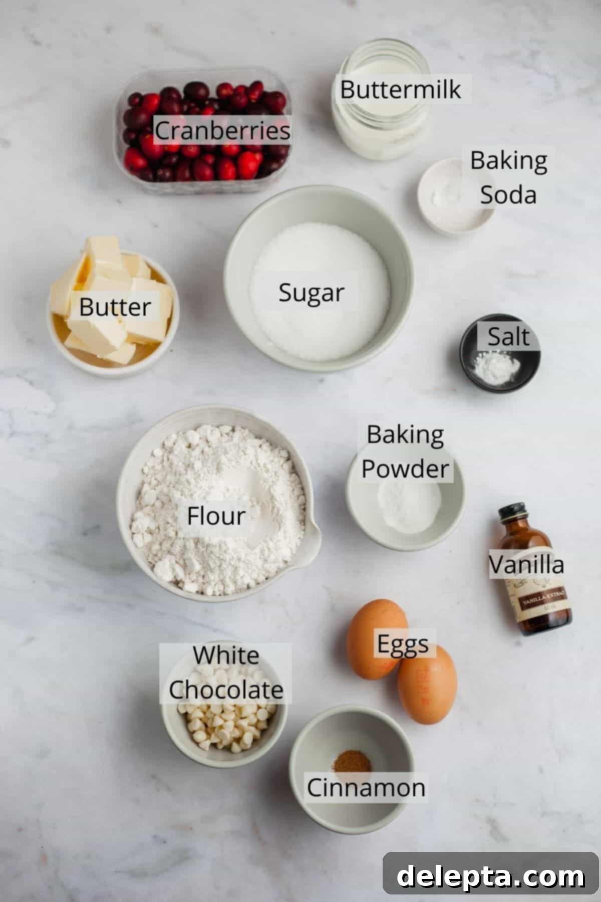 Bakery Fresh Cranberry White Chocolate Muffins 3 All the essential ingredients for making cranberry white chocolate muffins, meticulously weighed out and arranged in small, clear bowls on a light surface, showcasing fresh cranberries, white chocolate chips, flour, sugar, and more.