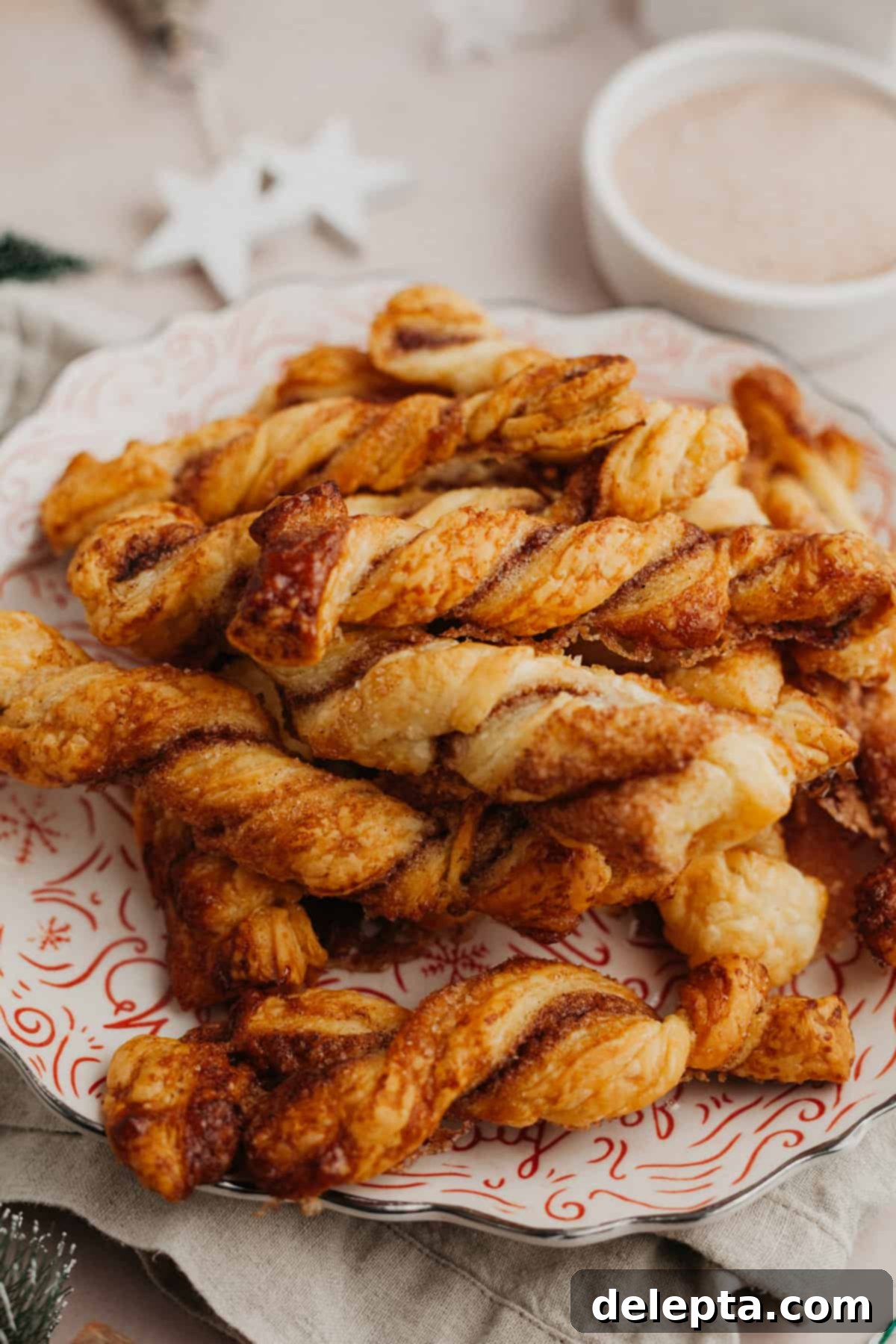 Flaky Cinnamon Twists 2 A small red and white plate filled with perfectly golden-brown cinnamon sugar twists, dusted with extra cinnamon sugar.