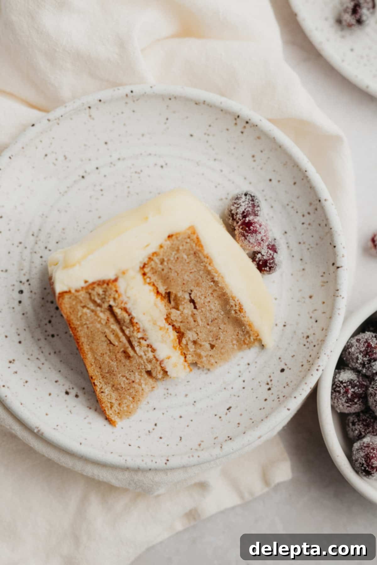 Frosted Peppermint Eggnog Drip Dream 11 A perfect slice of eggnog peppermint cake with white chocolate drip, served on a small plate.