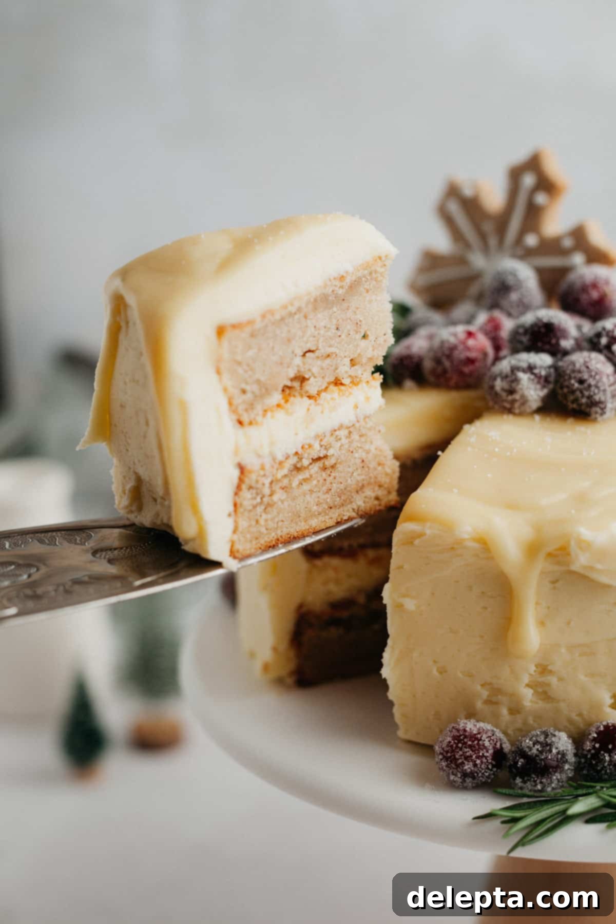 Frosted Peppermint Eggnog Drip Dream 10 A beautifully decorated white chocolate drip cake, covered in glistening sugared cranberries, with a slice being lifted out.