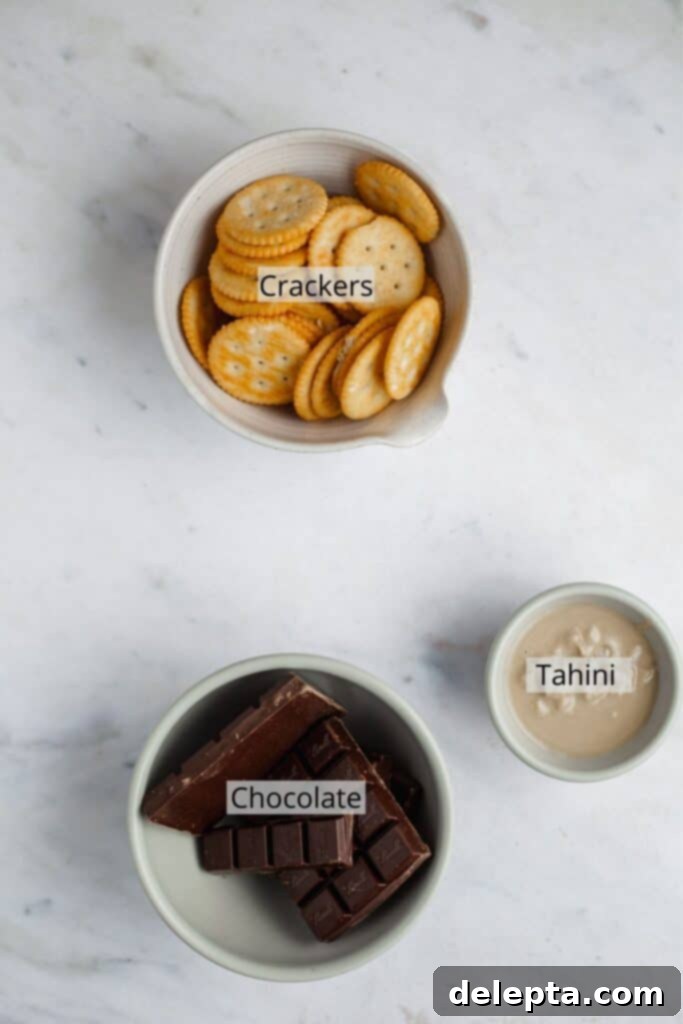 Effortless Holiday No-Bake Treats 3 Chopped dark chocolate in a bowl, Ritz crackers in a bowl, and a small bowl with tahini on a marble counter, ready for no-bake cookies.