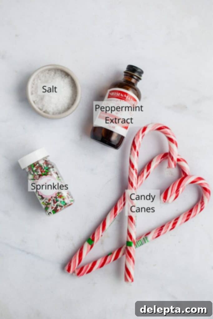 Effortless Holiday No-Bake Treats 4 Peppermint extract, three candy canes, colorful sprinkles, and a small bowl of flaky sea salt on a marble surface, representing various cookie toppings.