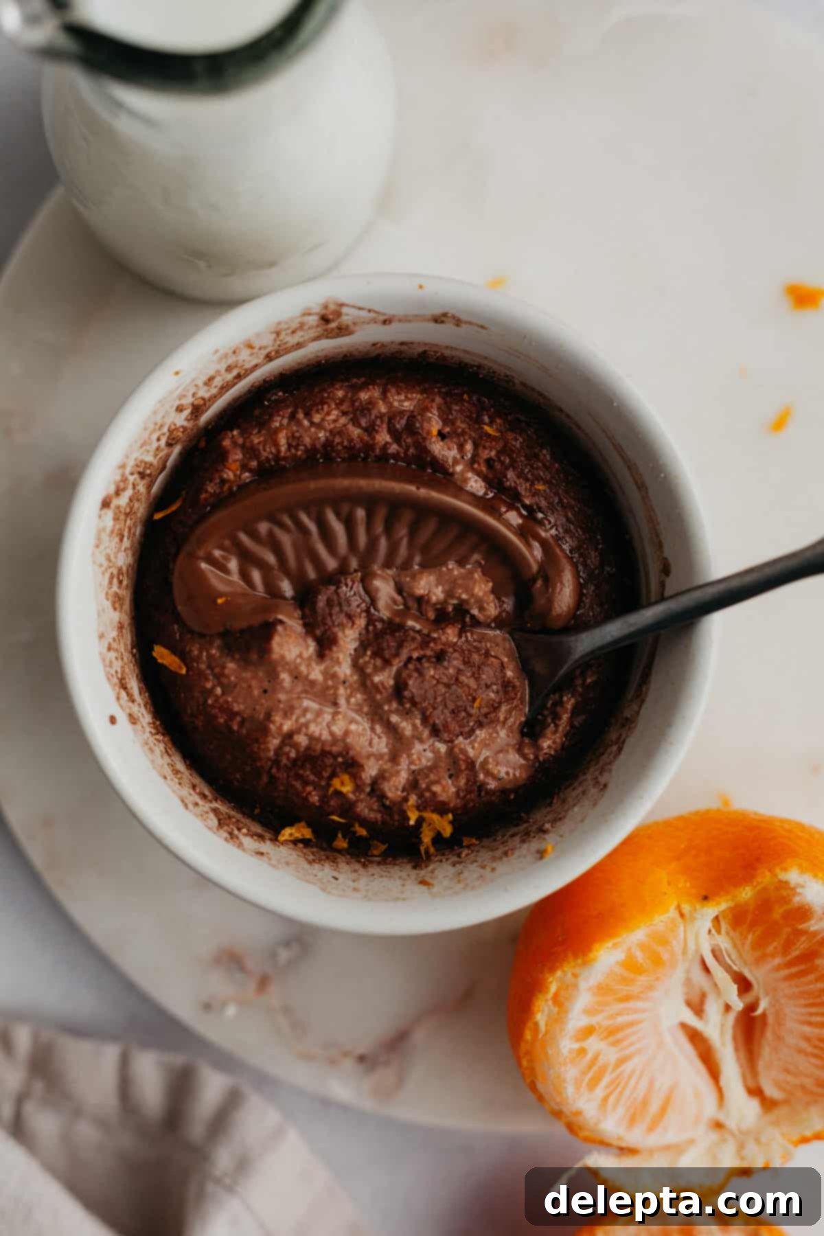 Sunshine Chocolate Orange Baked Oats 2 chocolate orange baked oats in a small white ramekin, topped with a melted chocolate orange segment.