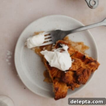 Fireside Bourbon Apple Pie 17 A slice of bourbon apple pie on a small plate. The pie has a dollop of whipped cream