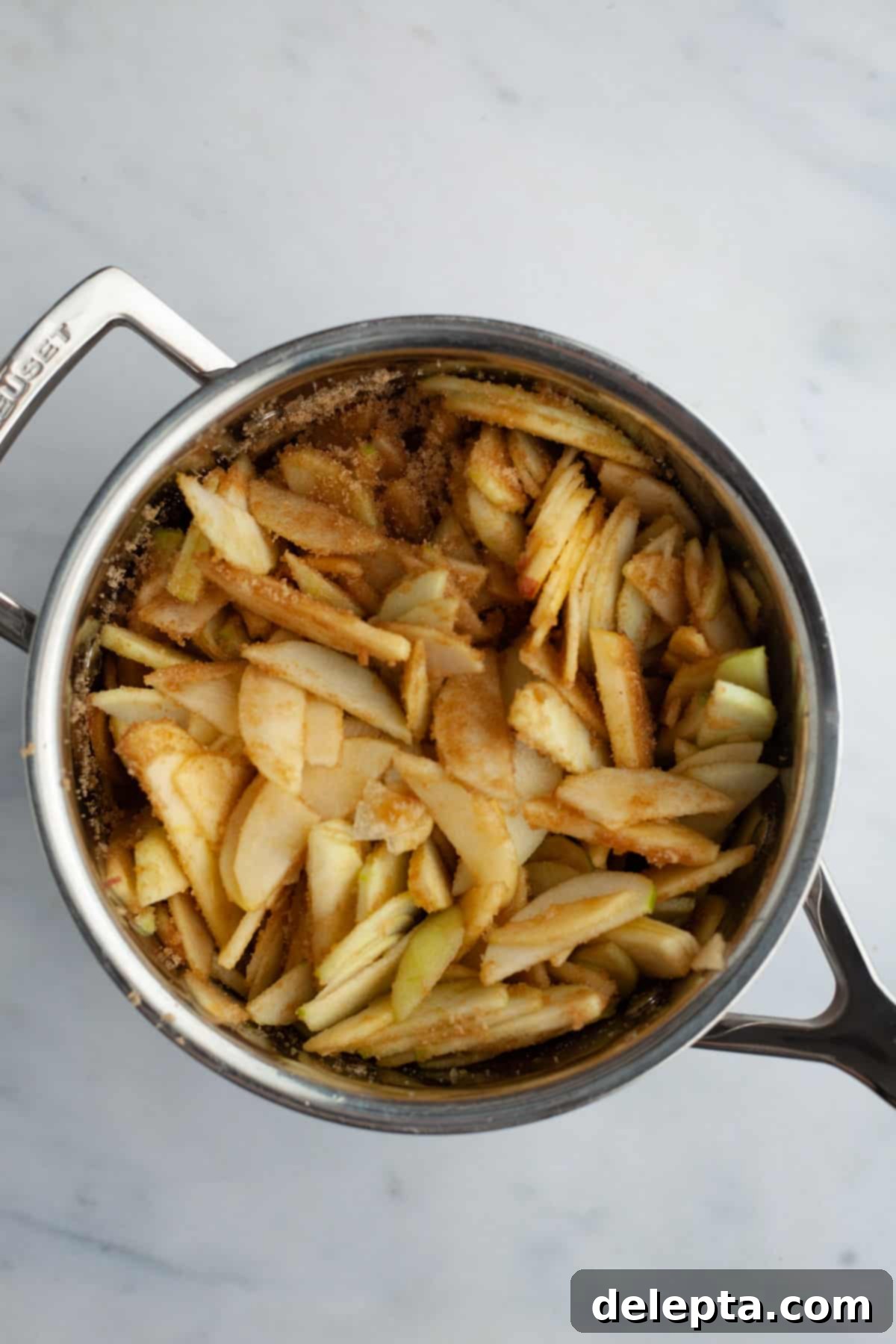 Fireside Bourbon Apple Pie 10 Thinly sliced apples, coated in cinnamon and brown sugar, macerating in a small saucepan before cooking.