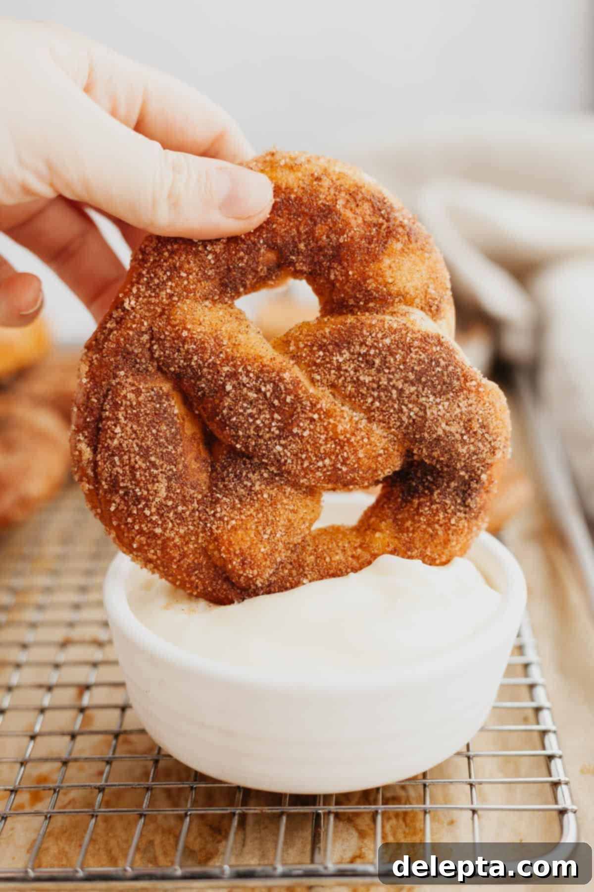 Warm Cinnamon Sugar Soft Pretzels 11 A sweet cinnamon sugar soft pretzel being dipped into a creamy white cream cheese dip.