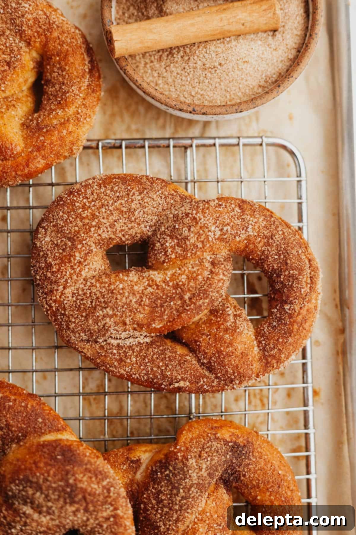 Warm Cinnamon Sugar Soft Pretzels 10 A freshly baked cinnamon sugar soft pretzel resting on a wire cooling rack, dusted with cinnamon sugar.