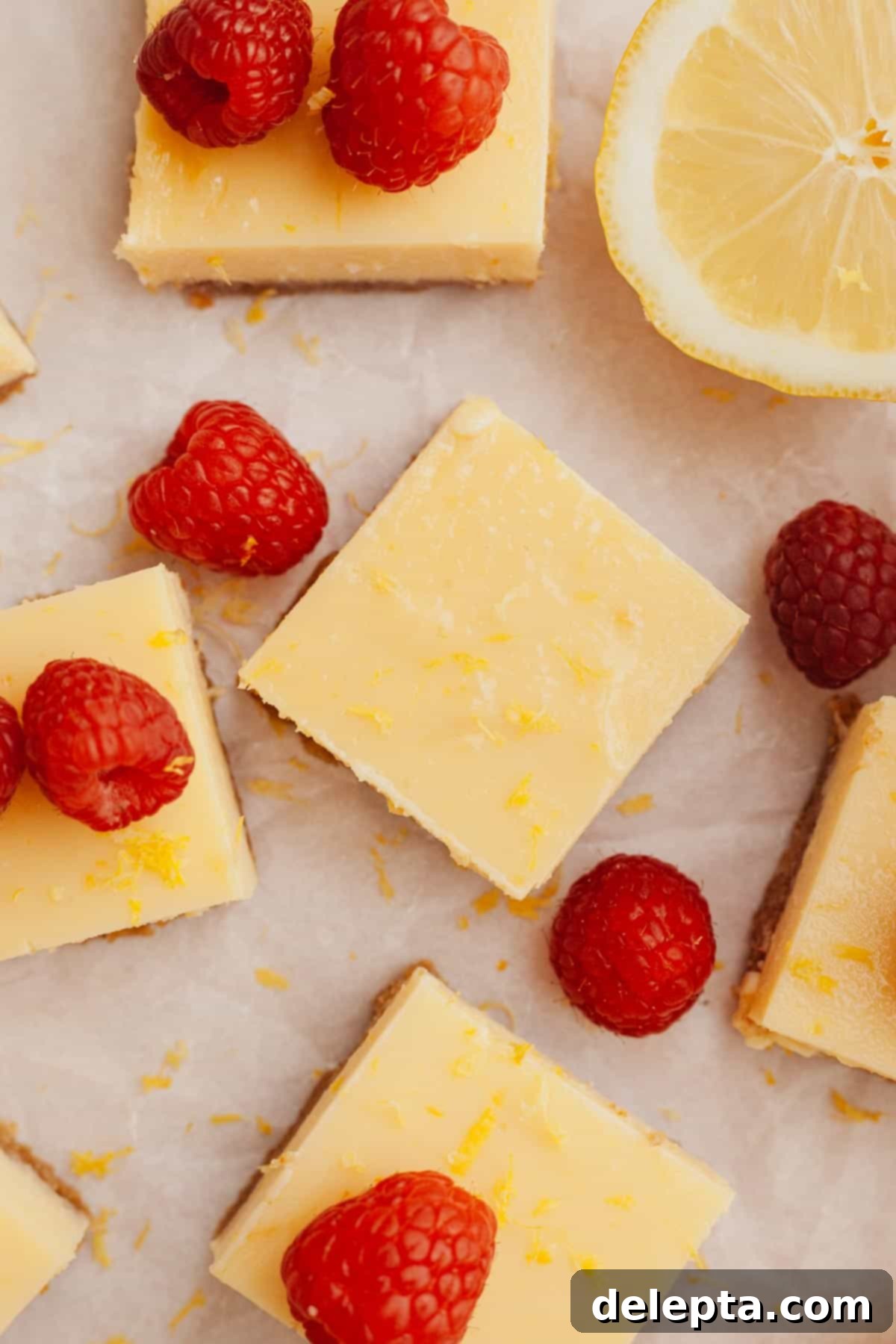 Zesty Lemon Squares with Buttery Graham Crust 6 Delicious lemon squares arranged on parchment paper, beautifully garnished with fresh raspberries for a touch of vibrant color and flavor.