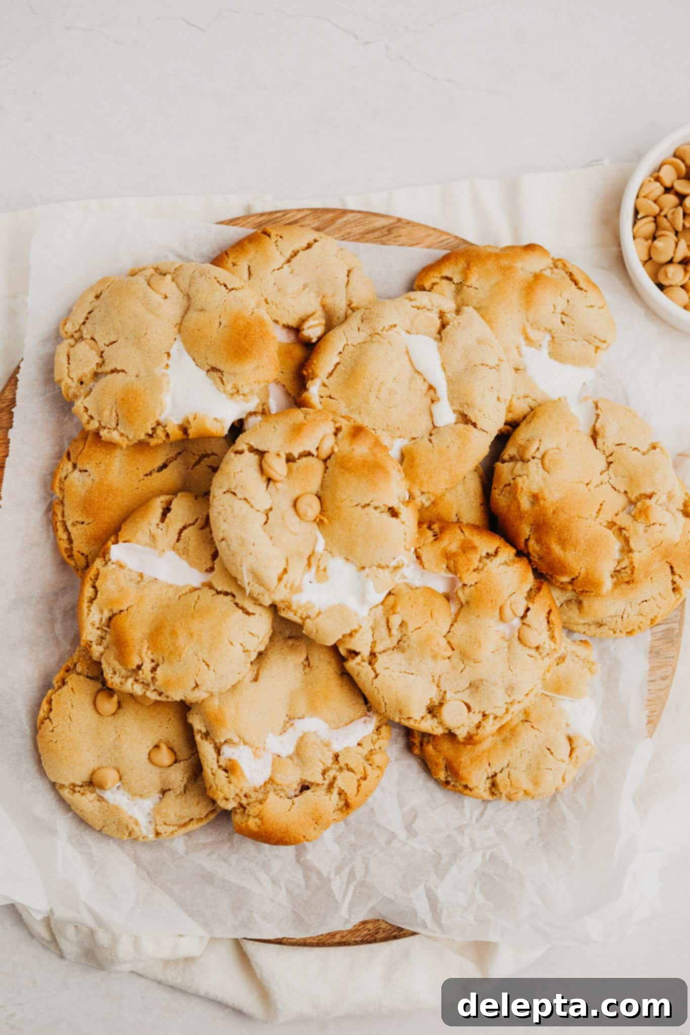 Peanut Butter Mallow Bliss Cookies 2 A delectable stack of soft and chewy peanut butter marshmallow cookies on parchment paper, showcasing their golden edges and gooey centers, inviting you to take a bite.