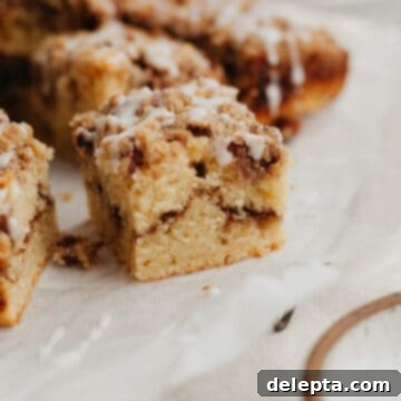 Heavenly Pecan Sour Cream Coffee Cake 11 A close up of a slice of pecan sour cream coffee cake on parchment paper, showing the beautiful layers and streusel.