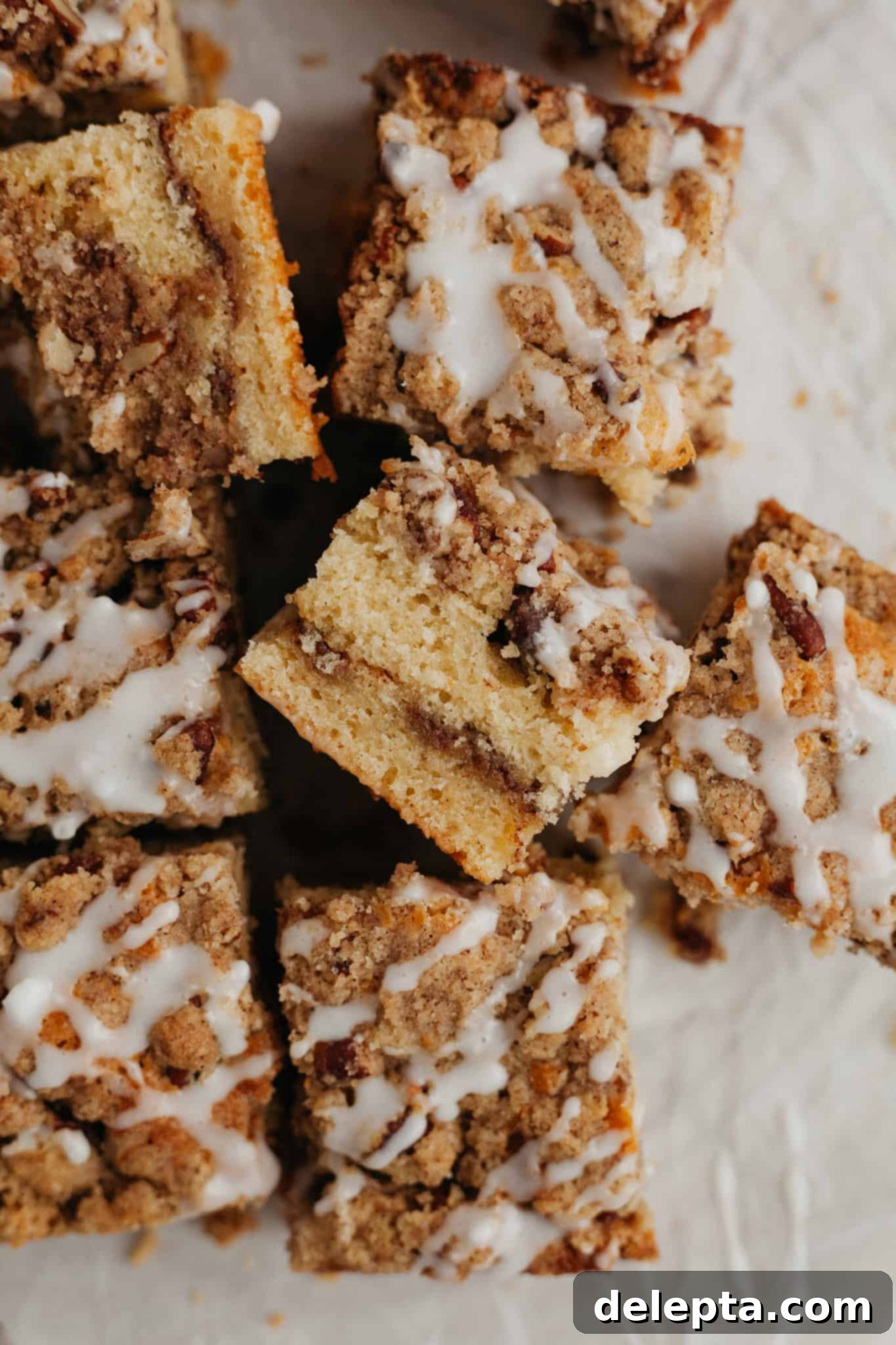 Heavenly Pecan Sour Cream Coffee Cake 9 Square slices of pecan sour cream coffee cake from above, one slice in the middle is turned on its' side to show the layers.