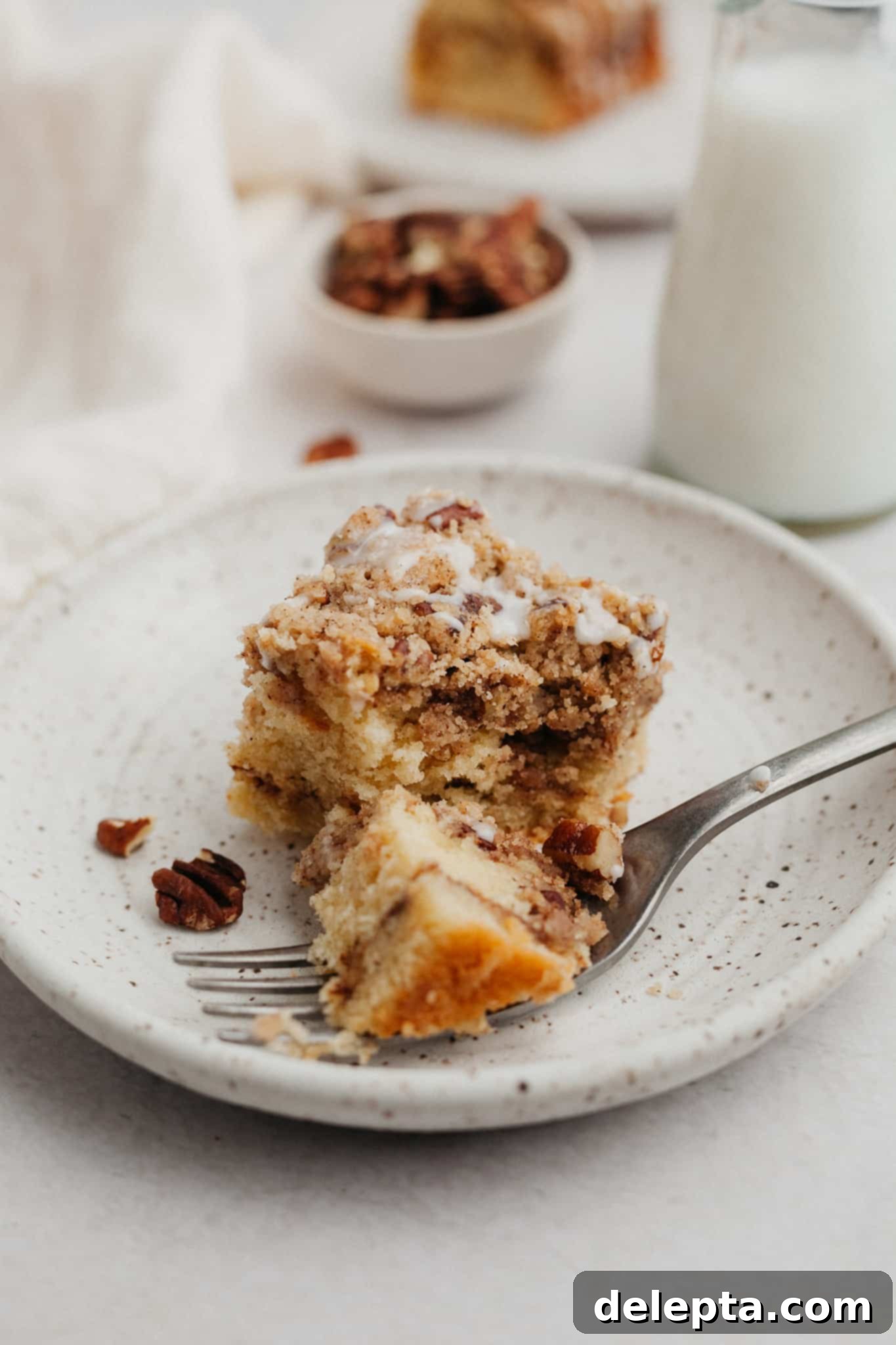 Heavenly Pecan Sour Cream Coffee Cake 10 A small plate with a slice of coffee cake on it, dusted with powdered sugar.