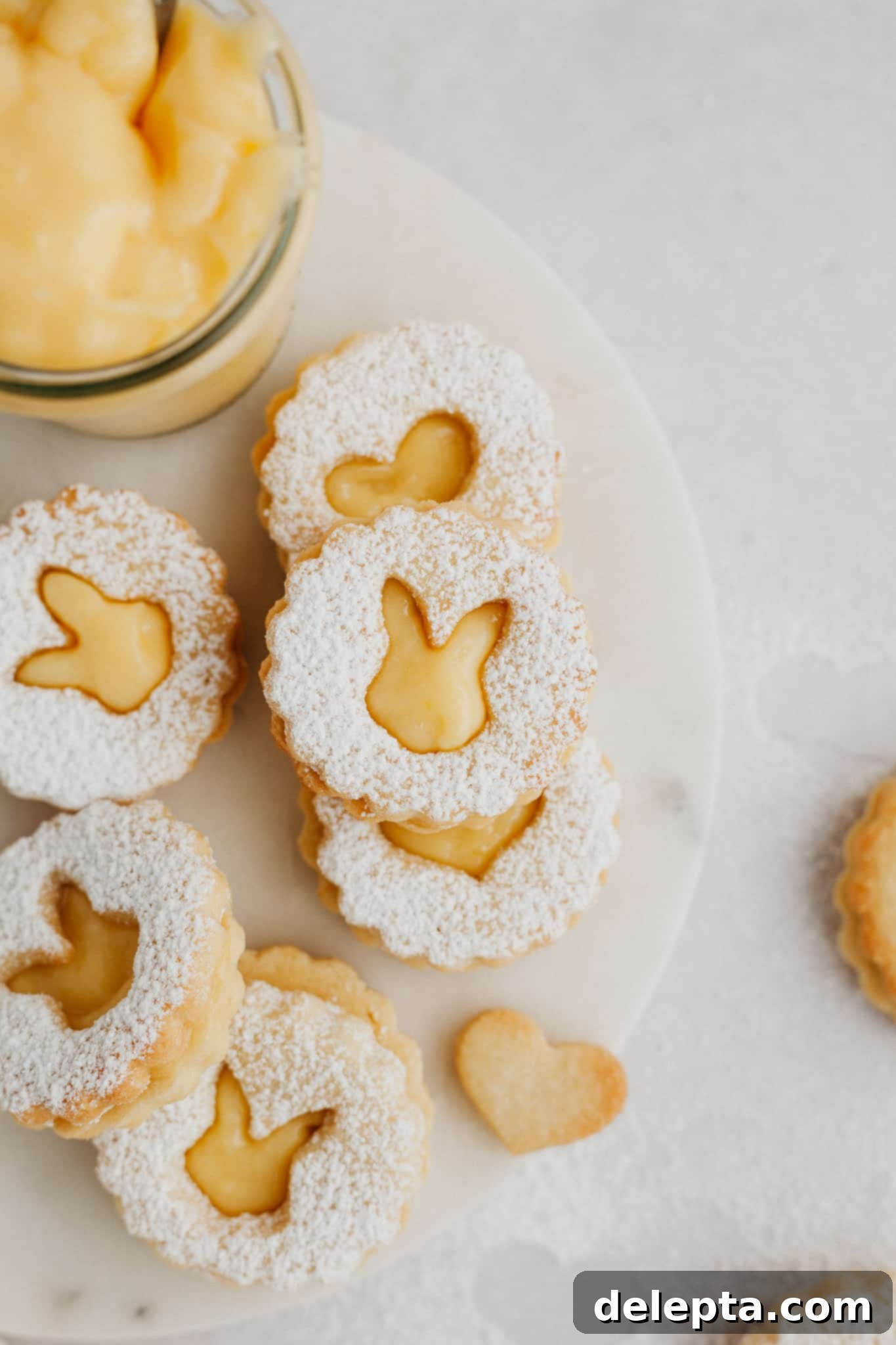 Zesty Lemon Curd Delights 11 Close-up of lemon curd linzer cookies with charming rabbit-shaped cutouts, elegantly displayed on a polished marble surface, highlighting their delicate details.