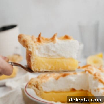 Lemon Cloud Dream 13 a slice of lemon meringue pie being lifted out with a serving knife.