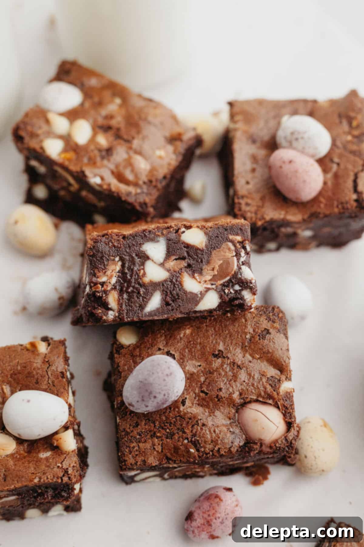 Rainbow Speckled Fudgy Mini Egg Brownies 8 A delectable spread of sliced mini egg brownies arranged on parchment paper, highlighting their fudgy interior and colorful toppings.