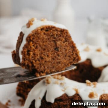 Golden Spiced Carrot Crown 8 A delectable slice of carrot bundt cake being gently lifted from the whole cake with a silver cake server.