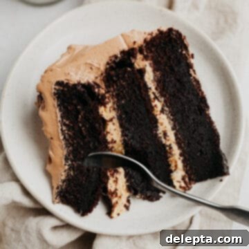 Peanut Butter Chocolate Nirvana 20 A slice of peanut butter and chocolate cake, made of three layers with a peanut butter filling, on a small beige plate.