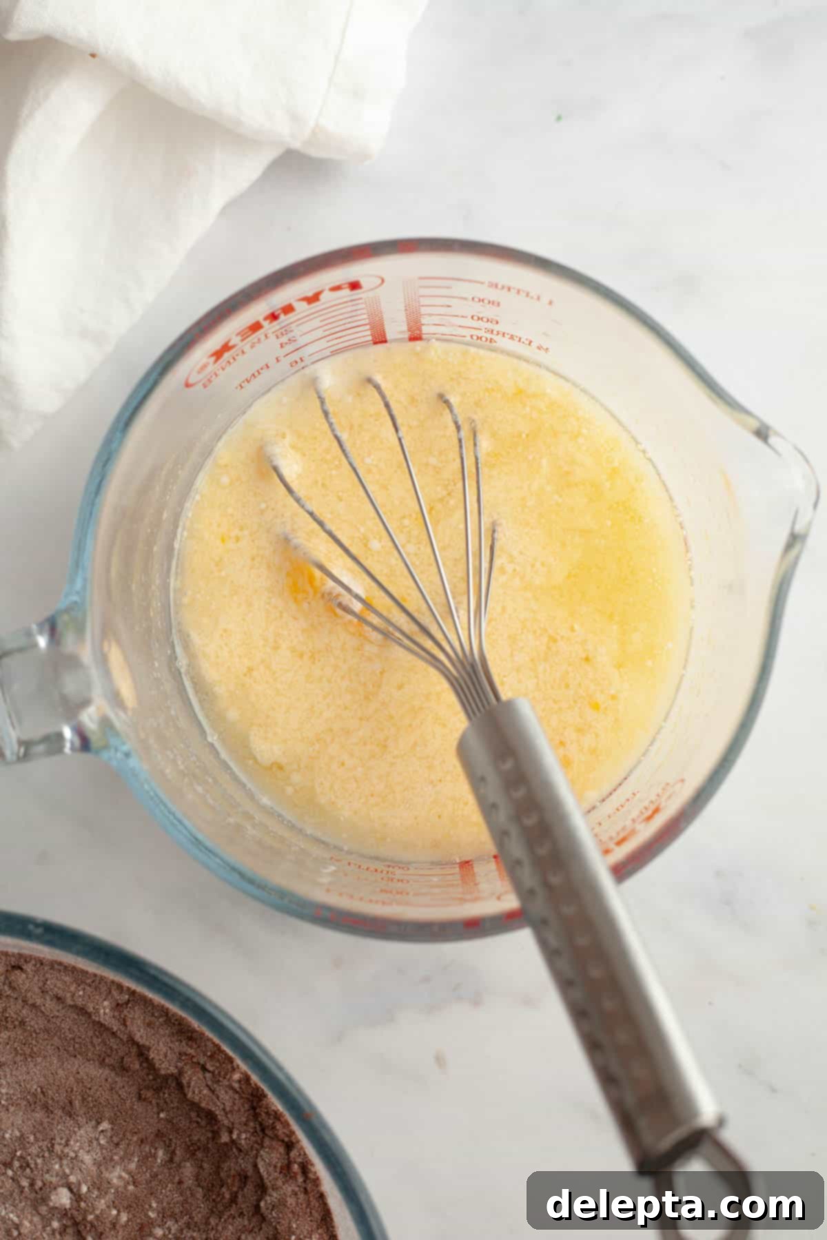 Matilda's 20 Minute Chocolate Cake 5 A jug with a whisk and a yellow mixture in it.
