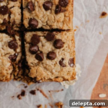 Chewy Peanut Butter Chocolate Chip Oat Bars 8 Sliced peanut butter oatmeal bars on parchment paper, ready to be enjoyed.