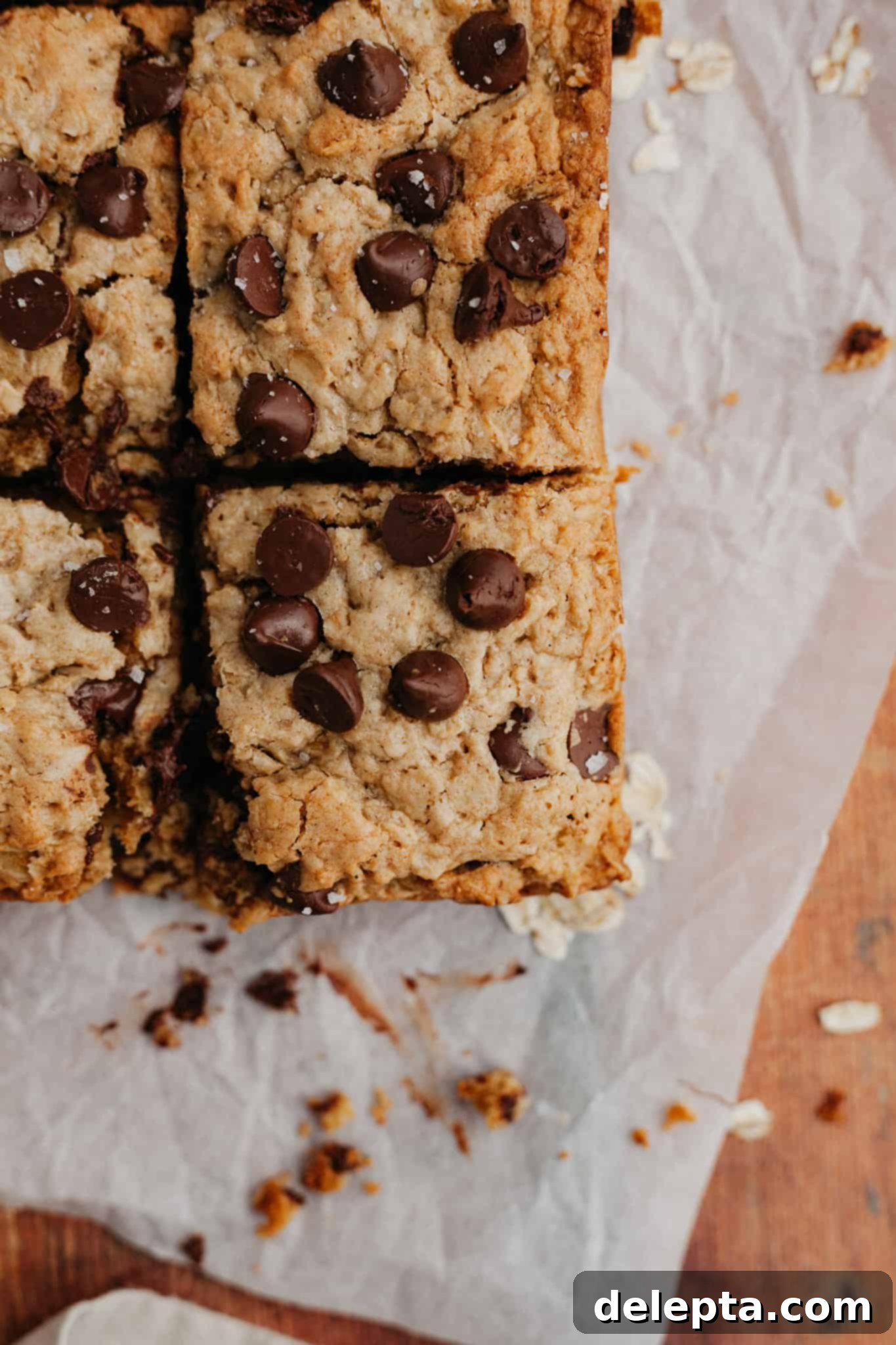 Chewy Peanut Butter Chocolate Chip Oat Bars 6 Sliced peanut butter oatmeal bars on parchment paper, showing their chewy interior and melted chocolate chips.