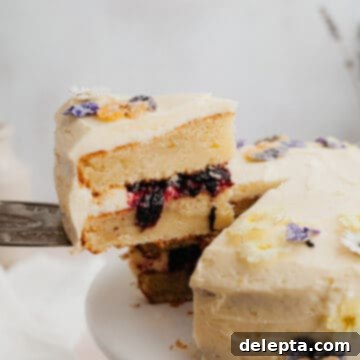 Zesty Lemon Blueberry Layer Cake 11 A yellow cake with a blueberry filling, a silver cake server is lifting one slice out.