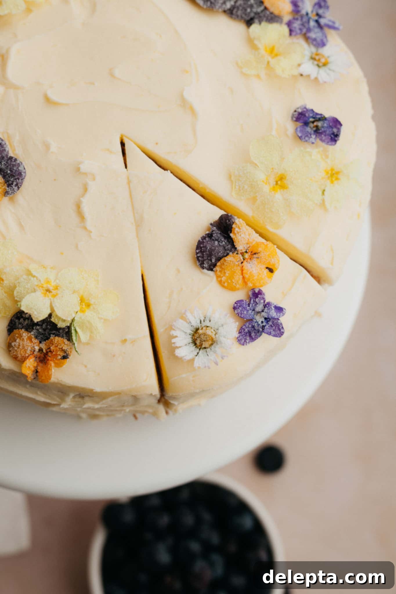 Zesty Lemon Blueberry Layer Cake 10 An inviting overhead shot of the beautifully frosted lemon blueberry cake, adorned with delicate candied flowers.