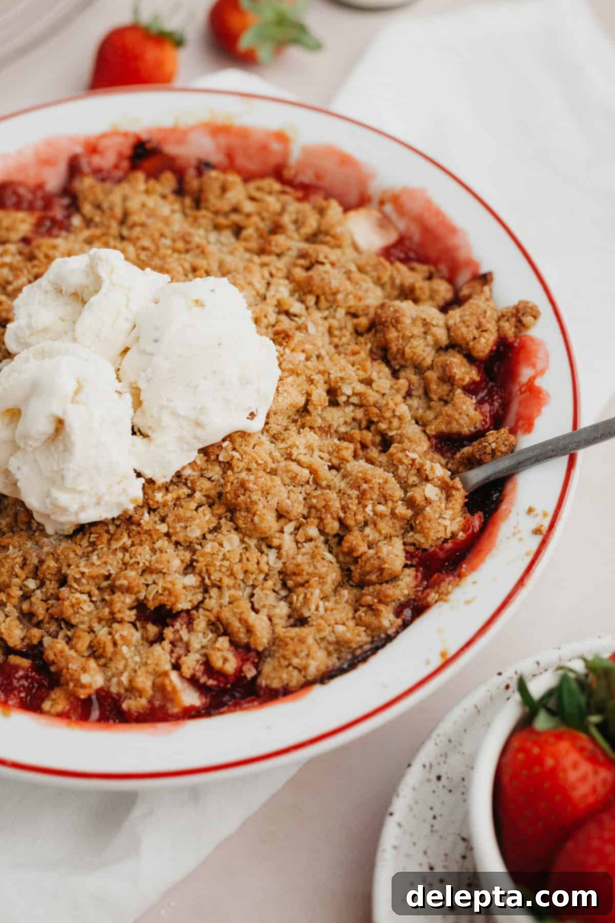 Simple Strawberry Apple Crisp 2 Strawberry and apple crisp in a white pie dish with several scoops of vanilla ice cream in the middle.