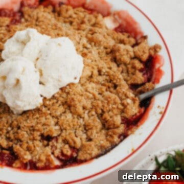 Simple Strawberry Apple Crisp 8 Strawberry and apple crisp in a white pie dish with several scoops of vanilla ice cream in the middle.