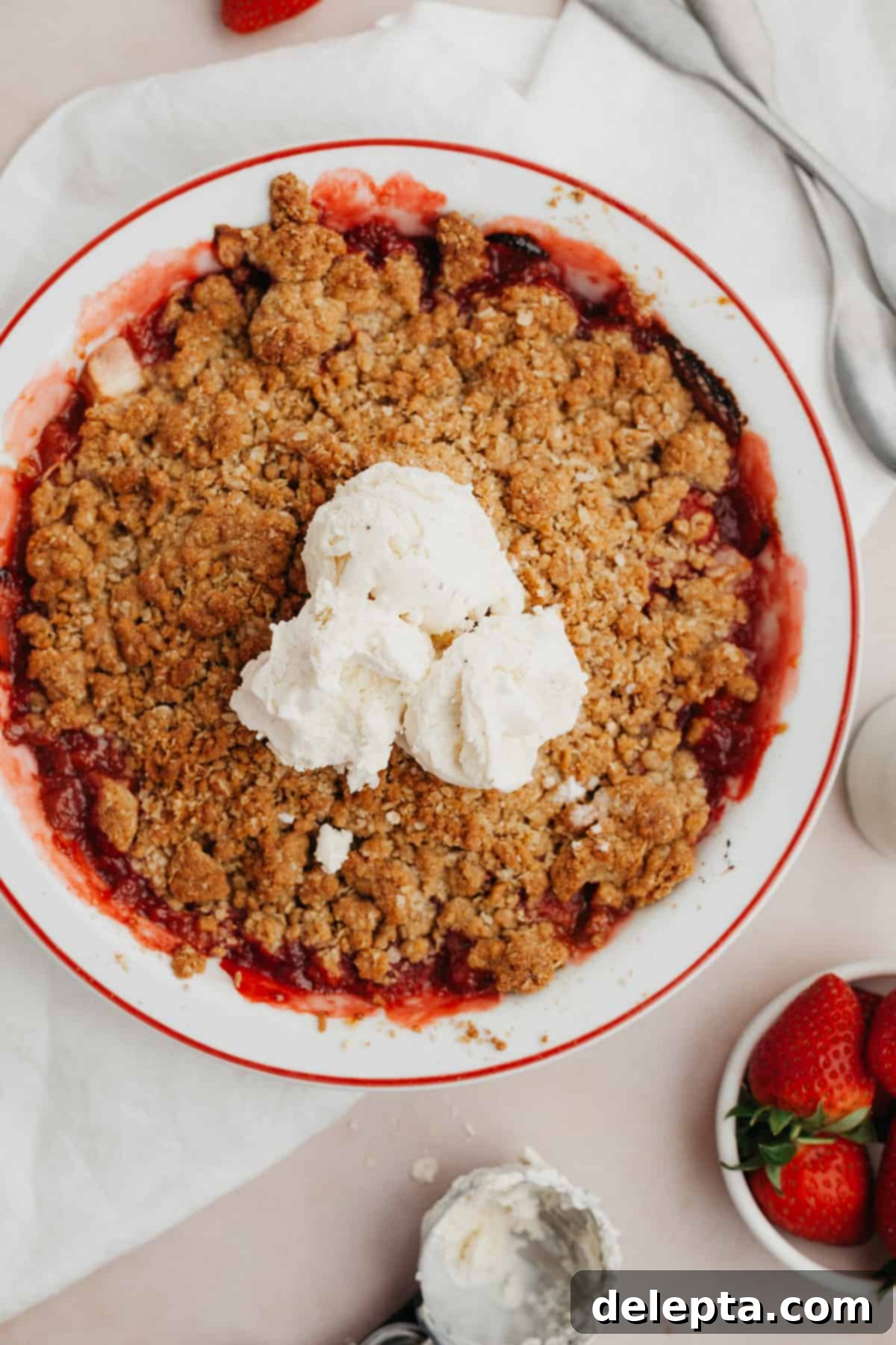 Simple Strawberry Apple Crisp 7 Strawberry and apple crisp in a white pie dish with several scoops of vanilla ice cream in the middle.