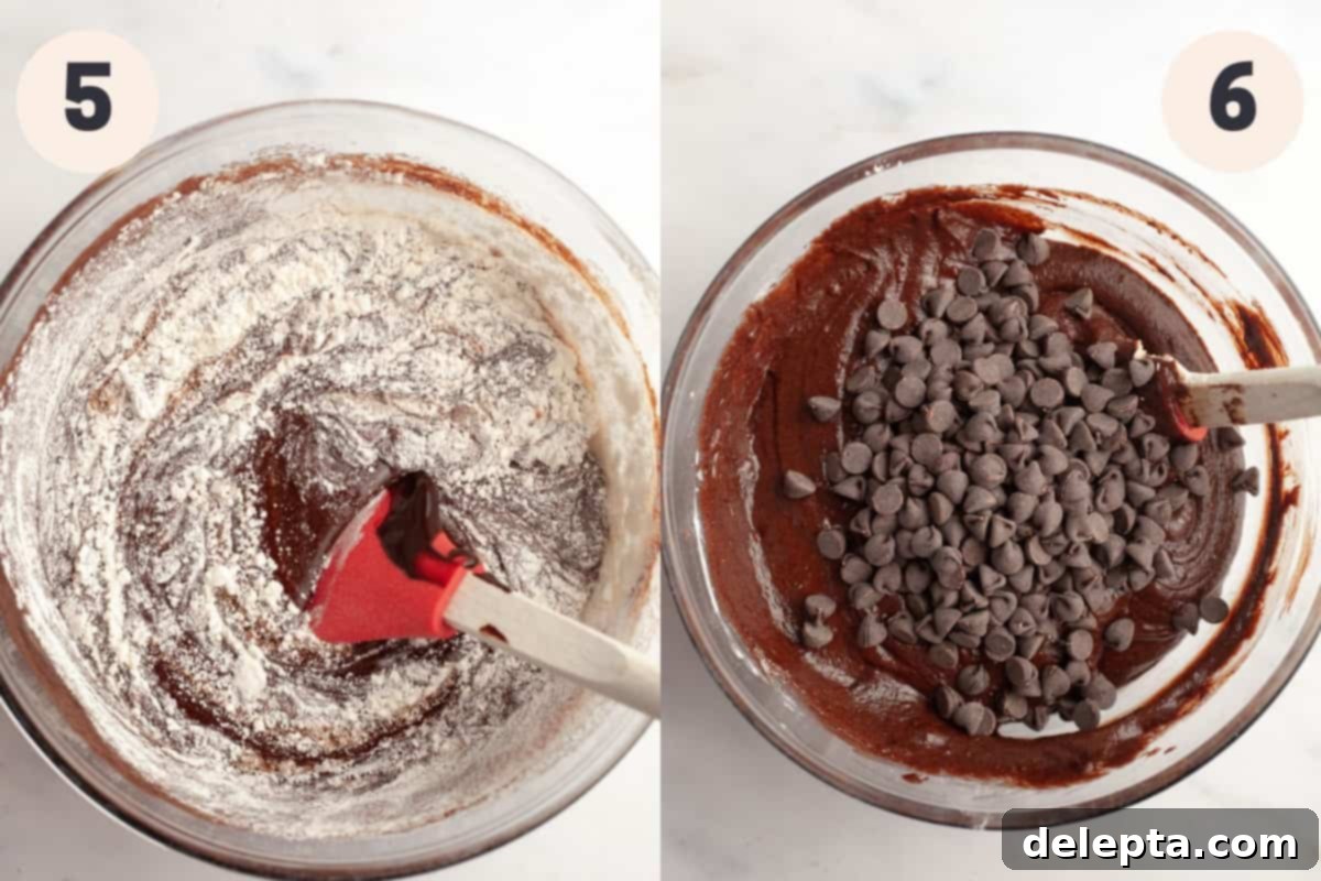 Decadent Fudgy Triple Chocolate Brownies 7 Thick, glossy brownie batter being mixed in a bowl, with a generous sprinkle of chocolate chips on top, ready for incorporation.