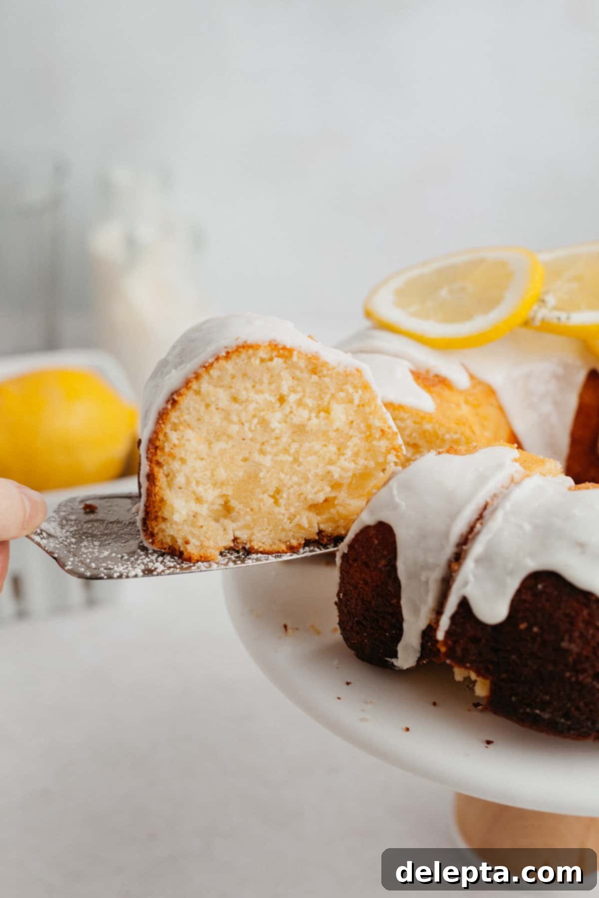 Sunny Lemon Bundt Bliss 7 A delicious slice of lemon bundt cake being served with a silver cake server, showing the moist interior.