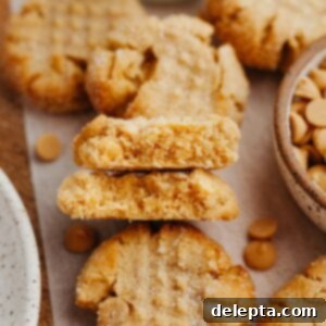 Peanut Butter Bliss in a Small Batch 8 Several peanut butter cookies on parchment paper, one cookie has been cut in half, the two halves are stacked on top of each other.